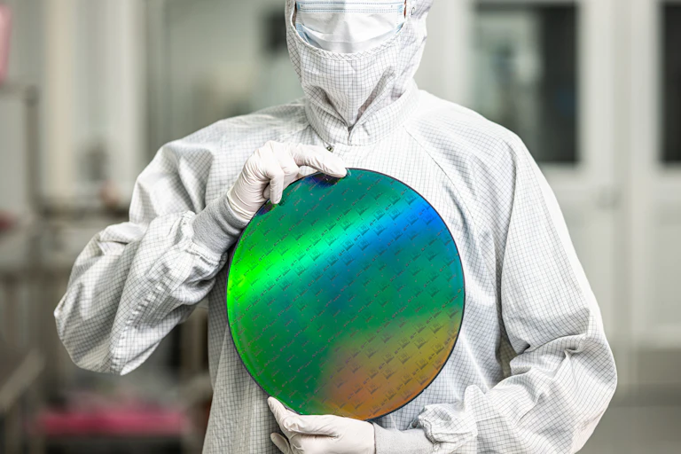 Photo of a man in a white suite holding a rainbow reflective circle.