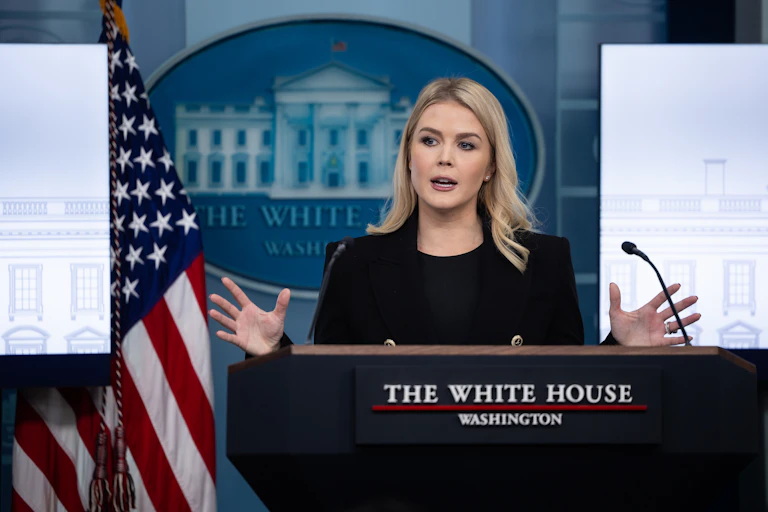 White House press secretary Karoline Leavitt gestures with her hands while stansing at a podium in the White House press briefing room