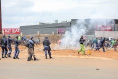 Police fire teargas at people who are blocking a road in a protest against not having water