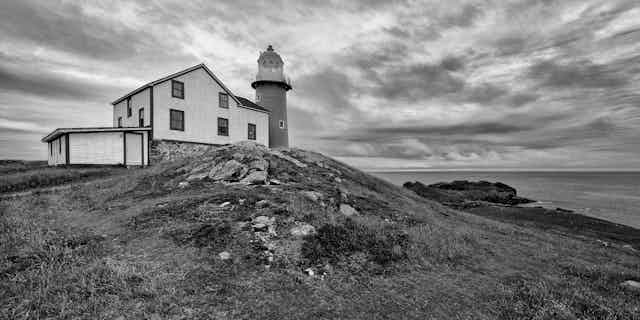 hut and lighthouse, by the coast, black and white image