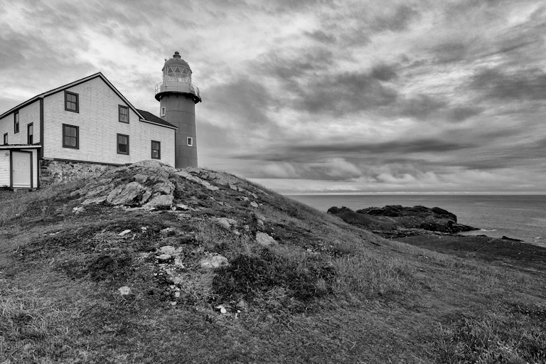 hut and lighthouse, by the coast, black and white image