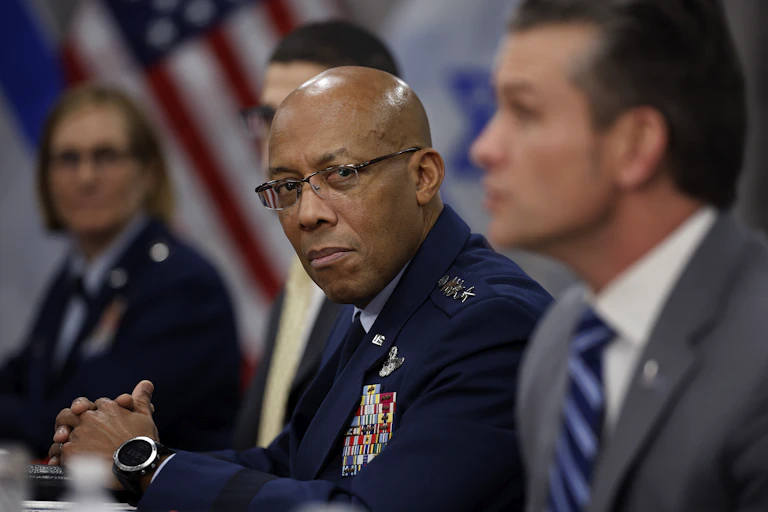 A man in a military uniform sits at a table with other people.