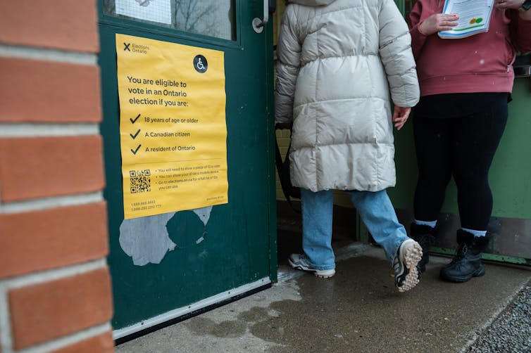 Personas que pasan por la puerta con una señal de votación amarilla