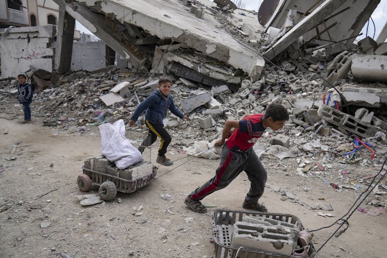 Des enfants traînent des paniers remplis de pierres