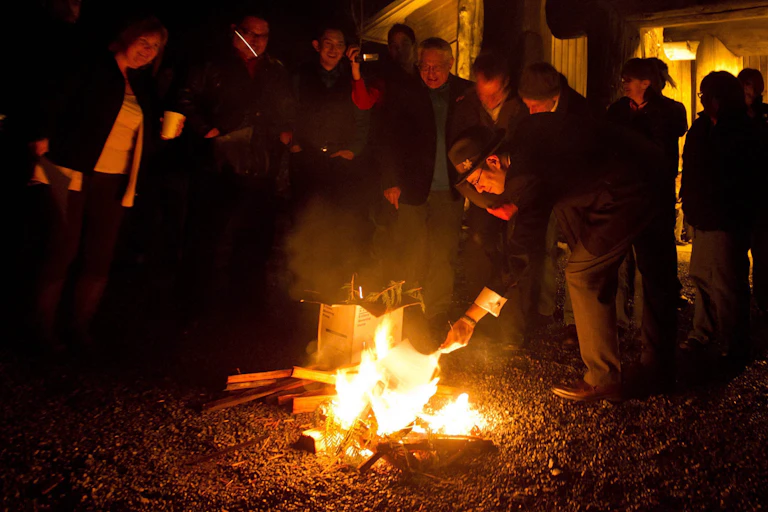 A group of people burn a document in an outdoor fire