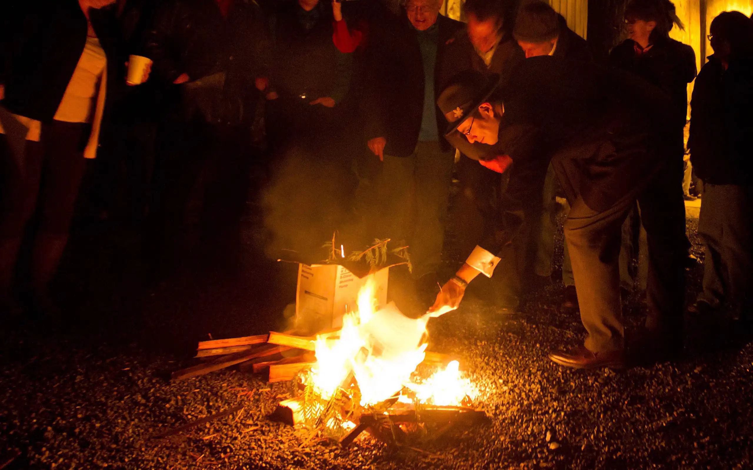 A group of people burn a document in an outdoor fire