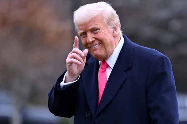 Un homme sourit en levant un doigt.