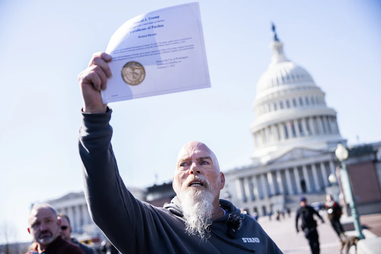 A man holds up an official document while standing in front of the U.S. Capitol building.
