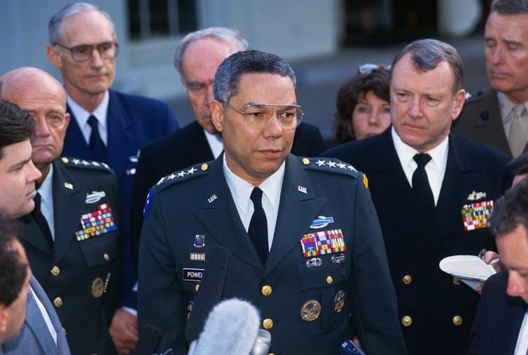 A man in a military uniform stands with other people in uniform.