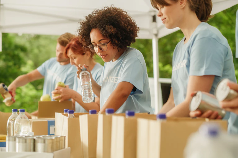 Volunteers packing paper bags with food and drink.