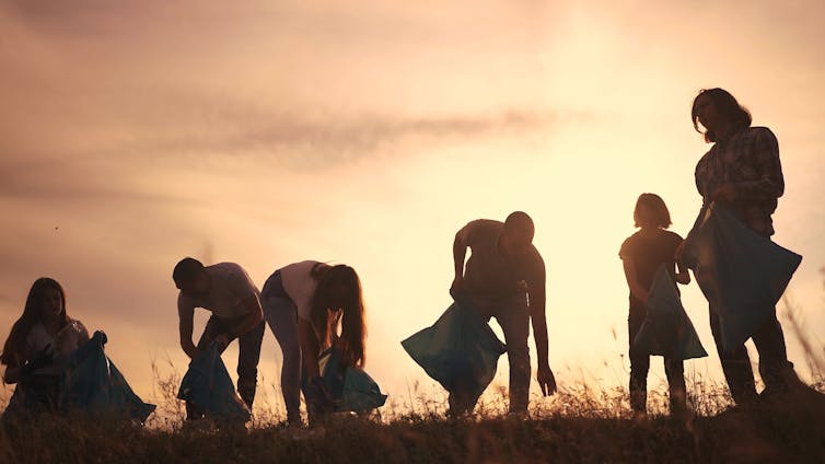 Silhouette of group picking litter.