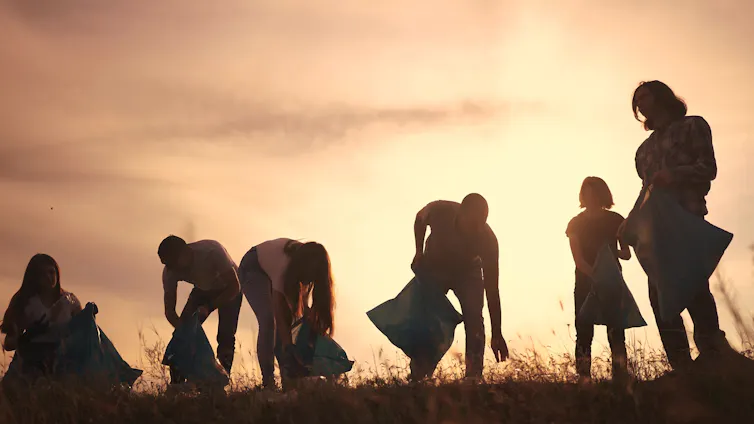 Silhouette of group picking litter.