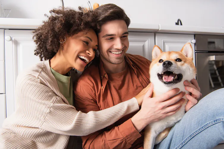A couple smiling with a dog