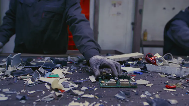 Photo of a person's hands sorting electronic waste.