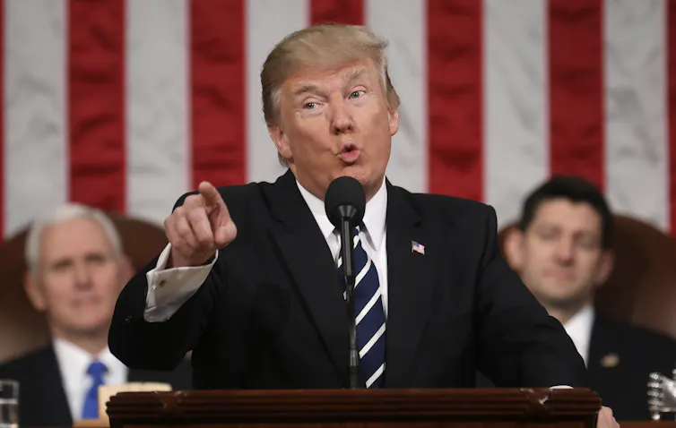 President Donald Trump standing in front of the American flag in Conress, pointing and talking.