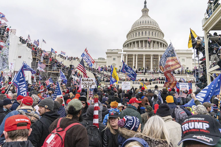 US capitol building with a Trump supporter crowd in front of it.