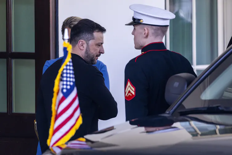 Ukrainian president, Volodomyr Zelensky, leaves the White House. In the foreground is a US military officer in dress uniform.