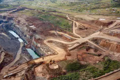 A giant open cast mine spreading out over kilometres. The land has been dug up and stripped of all vegetation and there are dirt roads and pits seen in its place