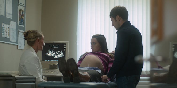 A mother and father at an ultrasound with a doctor.