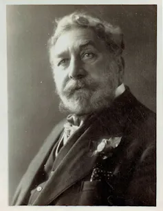 A black and white photo of a man with a strong moustache.