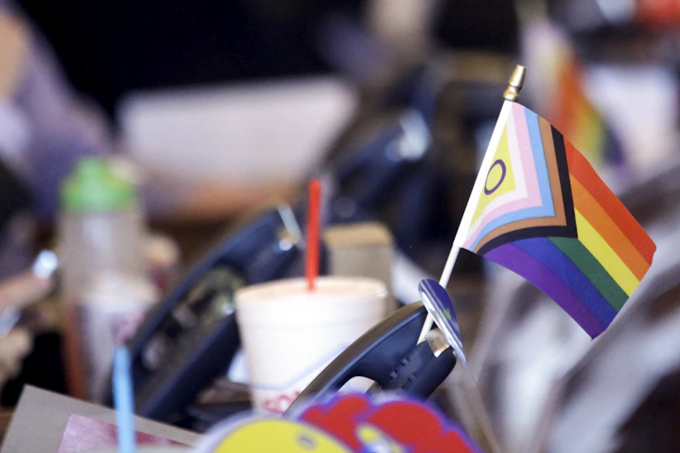 A trans pride flag seen on a desk.