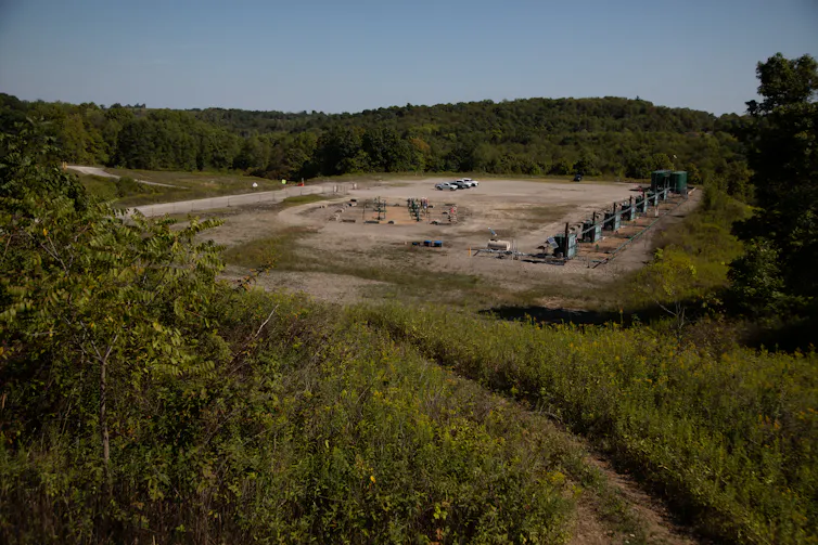 A flat, smooth area of dirt has trucks parked on it near industrial equipment.