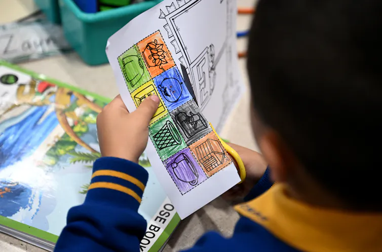 A primary student cuts square out of a work sheet.