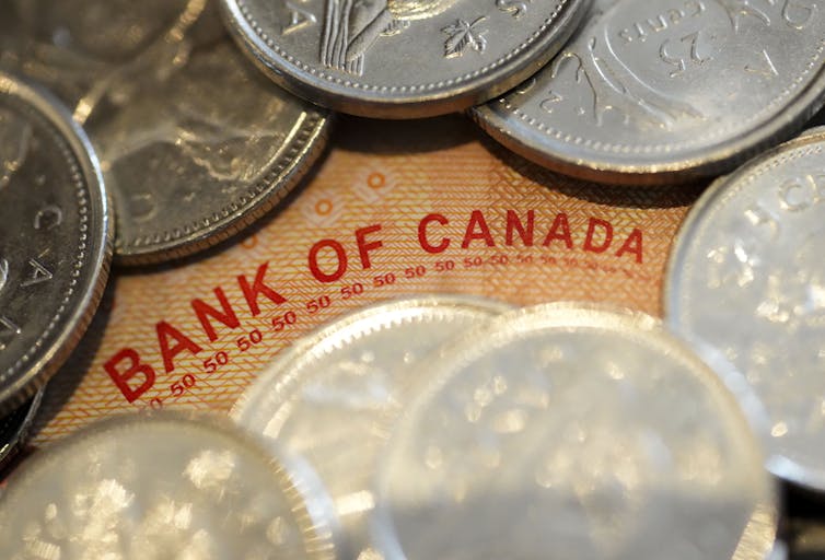 The phrase 'Bank of Canada' seen on a Canadian dollar bill surrounded by quarters