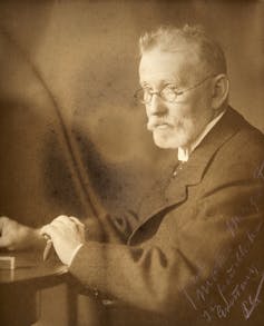 Sepia-toned photograph of a older man with a gray beard and glasses