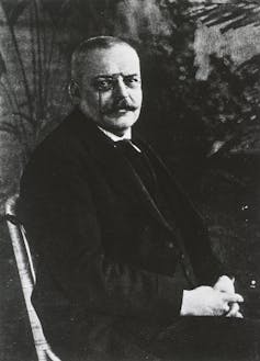 Black and white photo of a man with a mustache sitting in a chair