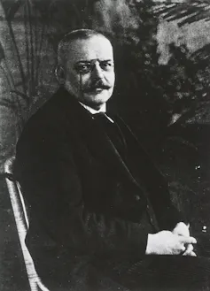 Black and white photo of a man with a mustache sitting in a chair