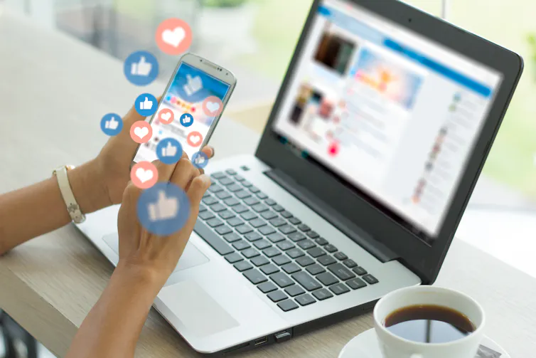 Young woman using smart phone, with lots of emojis popping out of the phone.