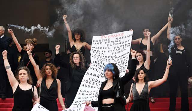 au Festival de Cannes en 2022, des membres du mouvement féministe « Les Colleuses » tiennent une banderole portant les noms de 129 victimes de féminicides.