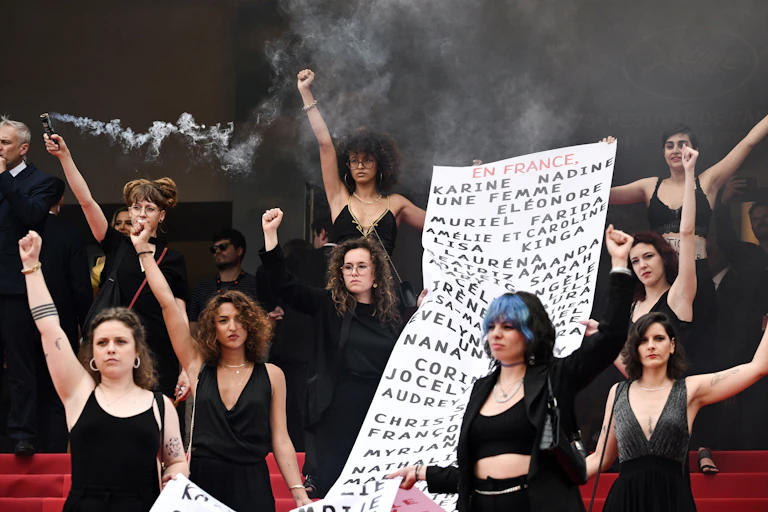 au Festival de Cannes en 2022, des membres du mouvement féministe « Les Colleuses » tiennent une banderole portant les noms de 129 victimes de féminicides.