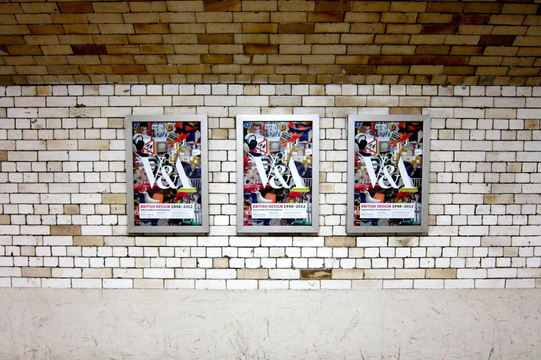 A tiled wall on the London Underground showing posters for a design exhibition at the V&A