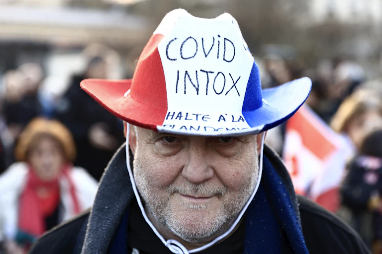 Homme portant un chapeau bleu blanc-rouge avec l'inscription «covid intox»
