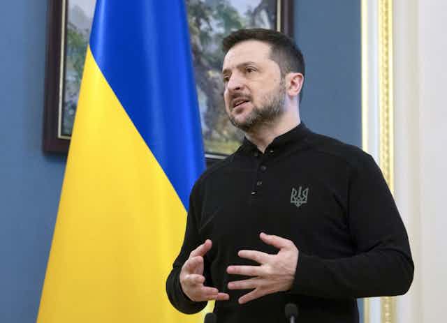 President Zelensky in front of a Ukraine flag.