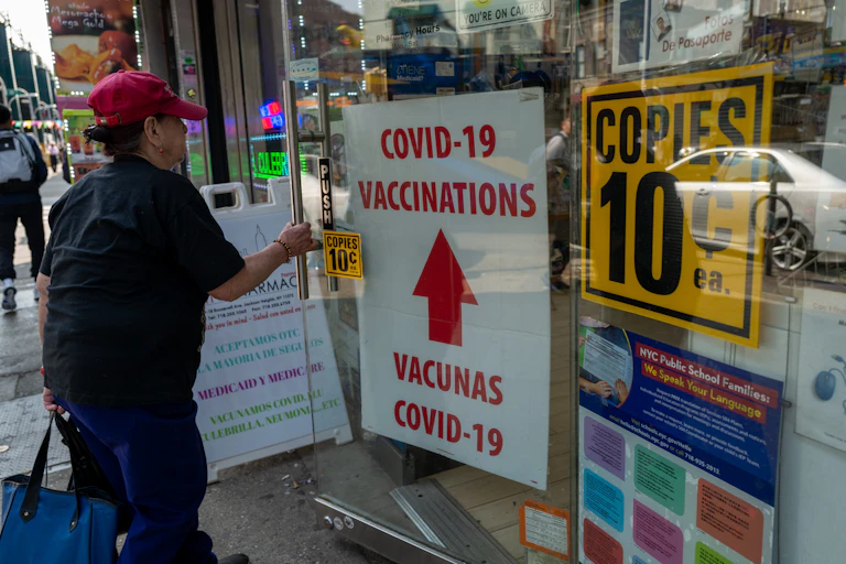person enters city pharmacy advertising COVID-19 vaccinations