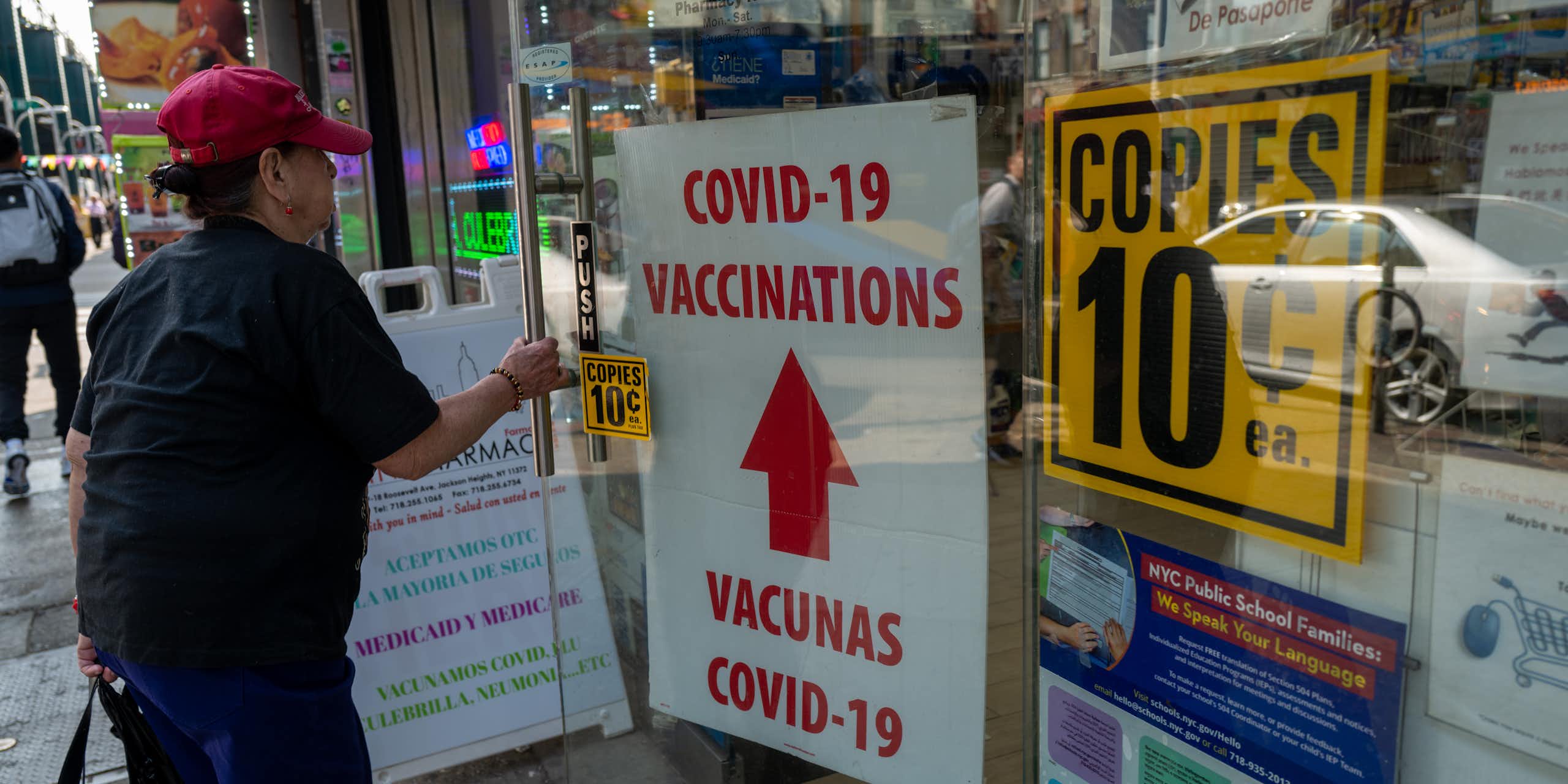person enters city pharmacy advertising COVID-19 vaccinations