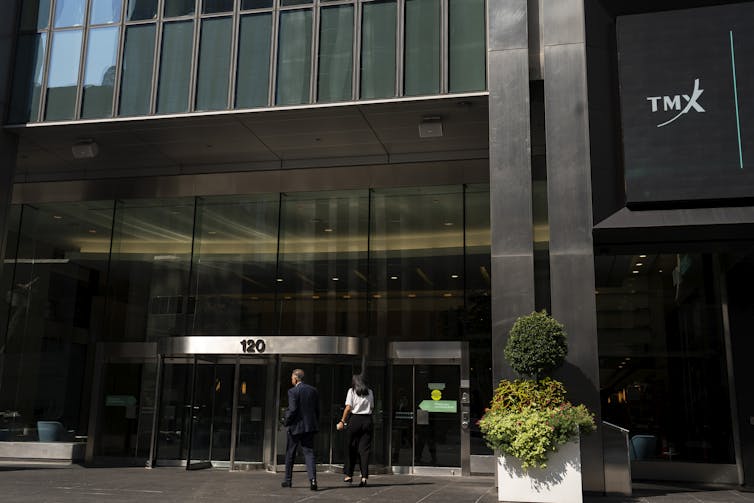 La gente camina frente a un edificio de vidrio