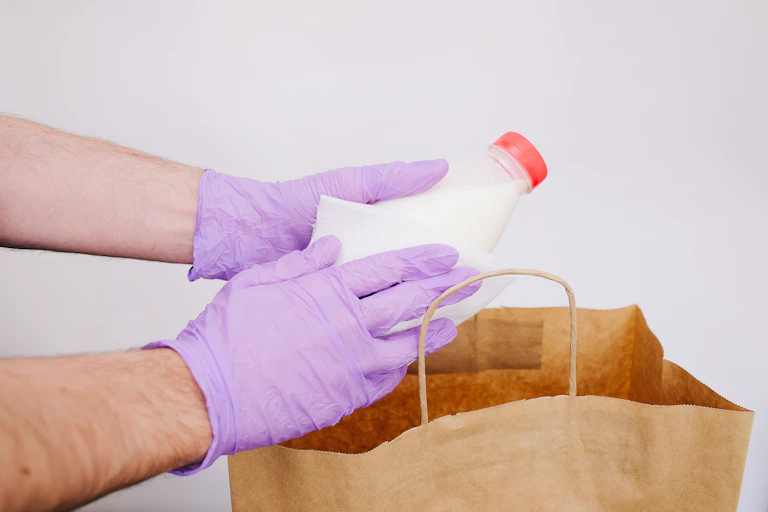 Person wiping down their groceries.