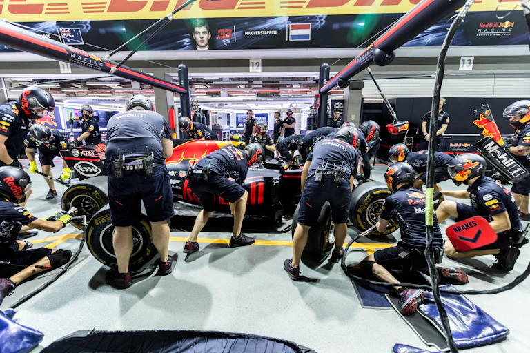 Max Verstappen and his pit crew team during an F1 pit stop.
