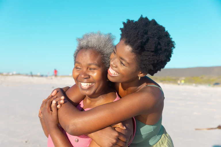 A black woman embracing her mother on a beach