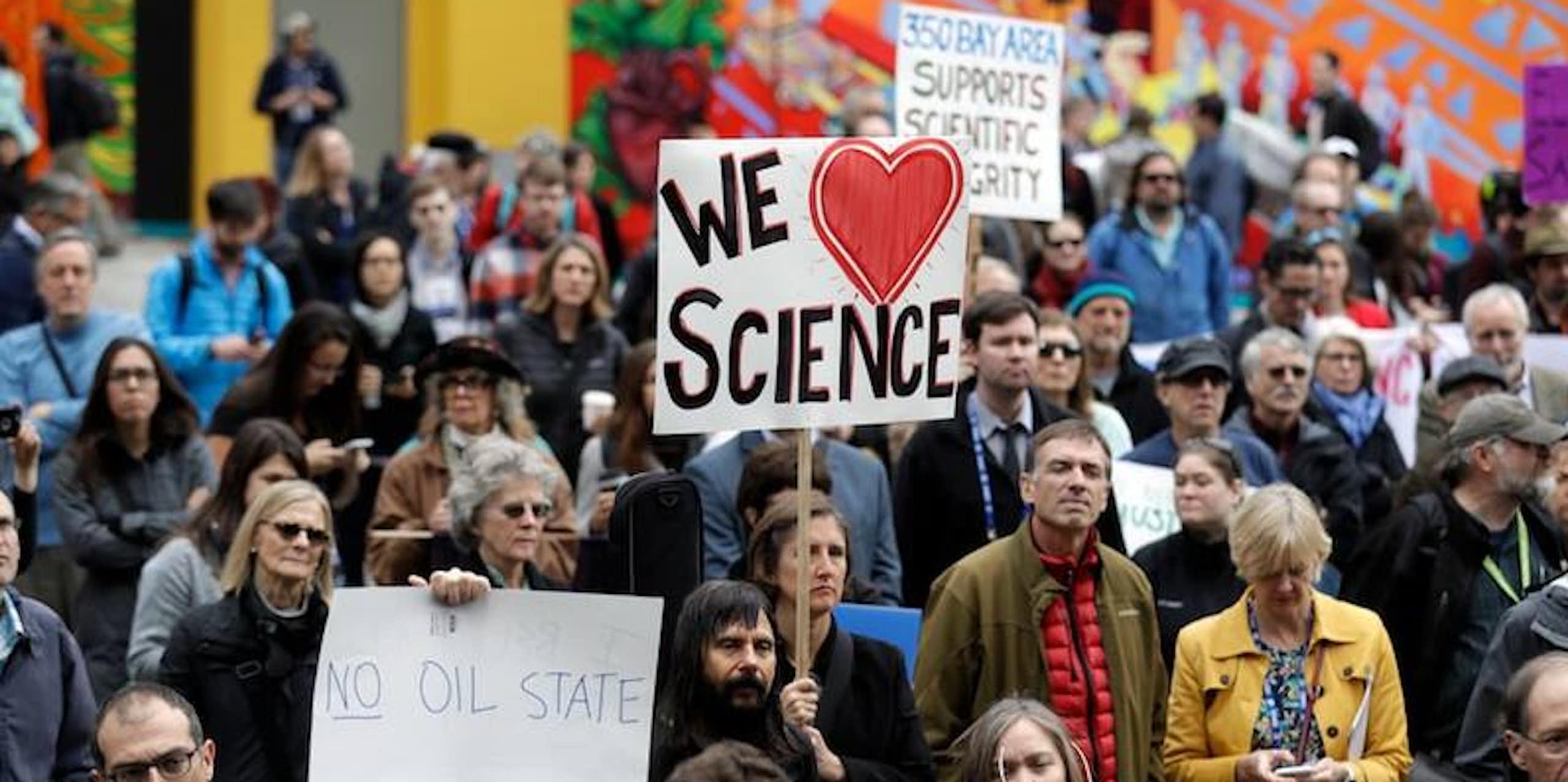 A crowd marching and holding signs saying We Love Science