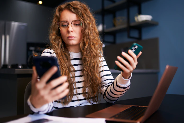 Une femme avec deux smartphones et un ordinateur. elle semble débordée