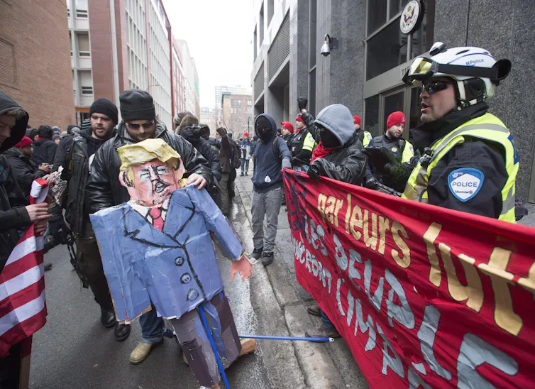Protesters hold up an effigy of Donald Trump as police look on.