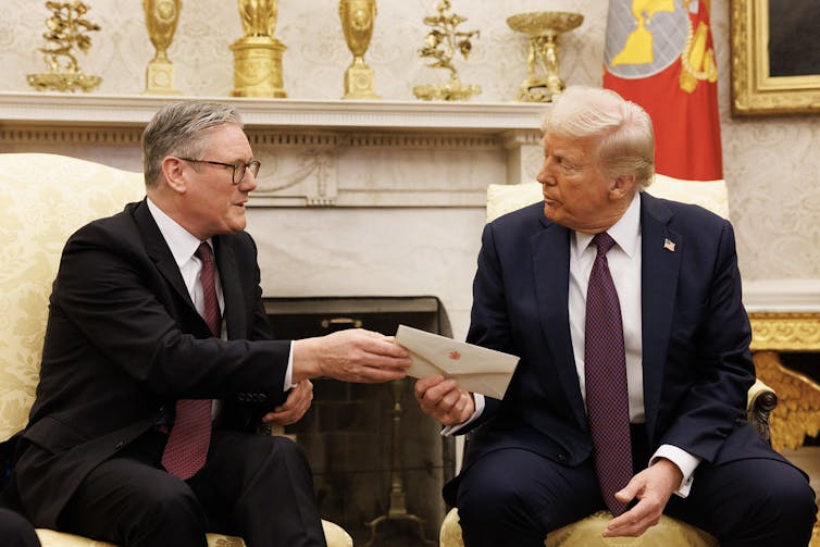 Keir Starmer handing Donald Trump an envelope while the two sit in the Oval Office