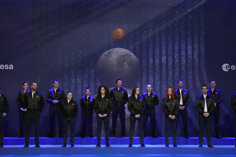 A group of people standing on a stage in front of the ESA logo and photos of the Moon and Mars.