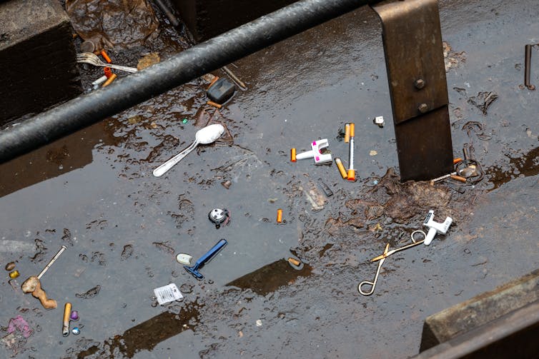 Used needly, Narcan dispensers and other items collects in large puddle on ground