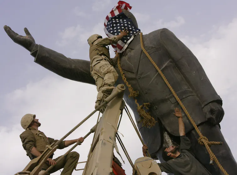 Statue of Saddam Hussein with US flag covering face is toppled by US soldiers